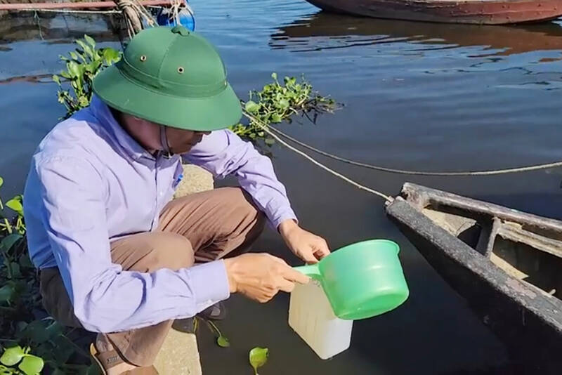 Cán bộ Chi cục Thủy sản Hà Tĩnh lấy mẫu nước ở khu vực nuôi cá lồng bè xã Thạch Sơn để tìm nguyên nhân cá chết. Ảnh: Trần Tuấn.