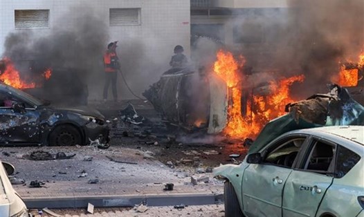 Người dân dập các đám cháy trên xe ôtô sau vụ tấn công bằng rocket từ Dải Gaza tại Ashkelon (Israel), ngày 7.10.2023. Ảnh: AFP/TTXVN