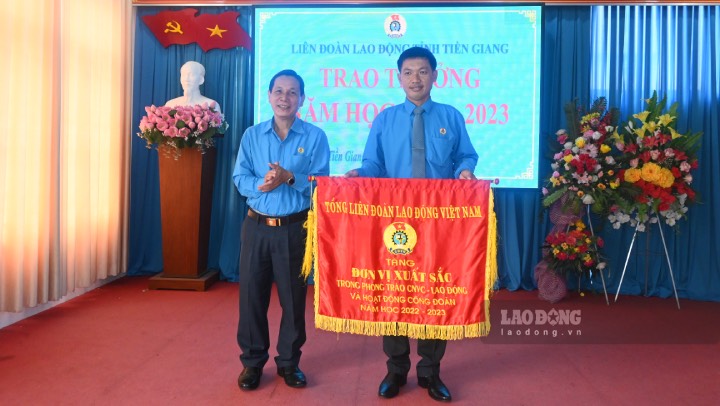Chủ tịch LĐLĐ tỉnh Tiền Giang Lê Minh Hùng trao tặng cờ thi đua và chúc mừng tập thể có thành tích xuất sắc. Ảnh: Thành Nhân