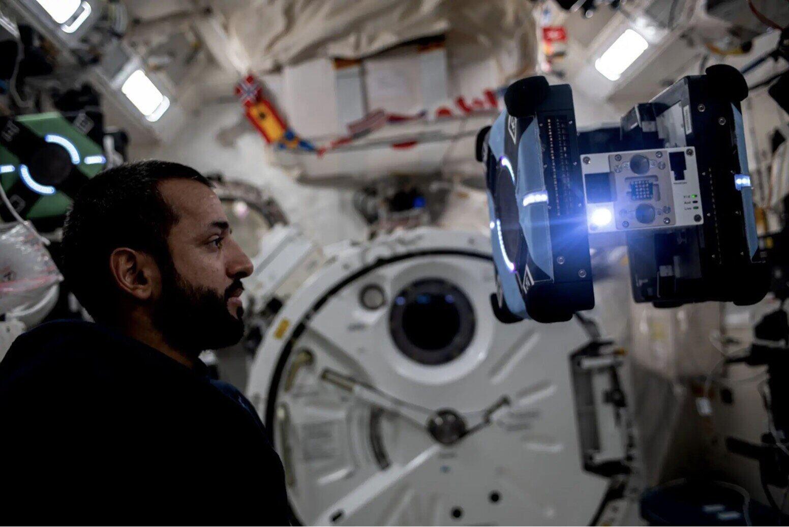 Phi hành gia từ Các tiểu vương quốc Ả Rập thống nhất quan sát trợ lý robot Astrobee bay tự do trong quá trình thử nghiệm hoạt động của nó. Ảnh: NASA