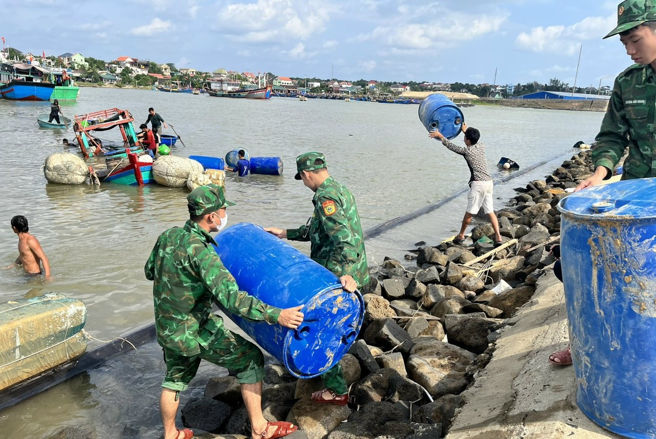 Lực lượng biên phòng vận chuyển các thùng nhựa làm phao nổi cho chiếc tàu chìm. Ảnh: T.Dũng.