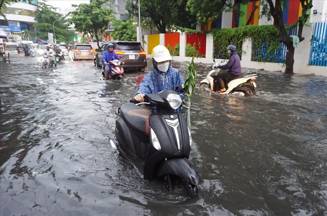 Người dân bì bõm lội nước sau một trận mưa lớn trên đường Quốc Hương, TP Thủ Đức. Ảnh: Minh Quân