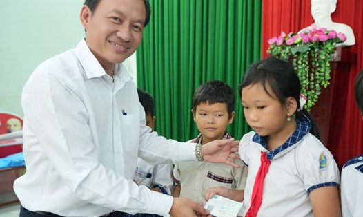 Phó Chủ tịch HĐND huyện Tam Nông, tỉnh Đồng Tháp Trần Thanh Sang, trao thẻ BHYT cho học sinh có hoàn cảnh khó khăn. Ảnh: BTC  