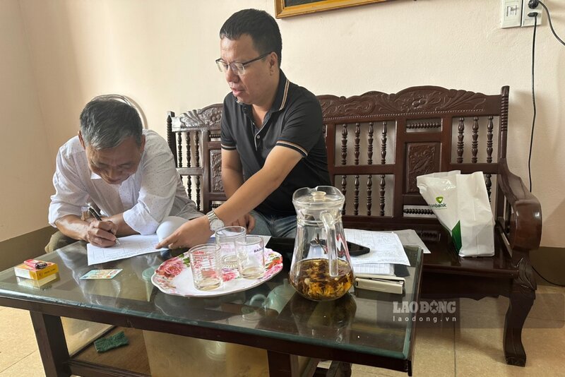 Ông Lừng (bên trái) vui vẻ ký nhận tiền đền bù. Ảnh: UBND xã Đồng Lương.