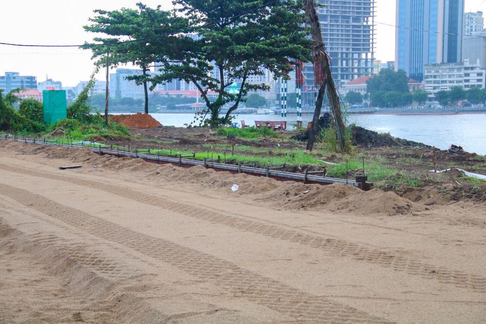 Hàng rào cỏ lau phủ kín bờ đông sông Sài Gòn đã được công nhân dọn dẹp, đường bờ kè được đổ cát, san phẳng. 