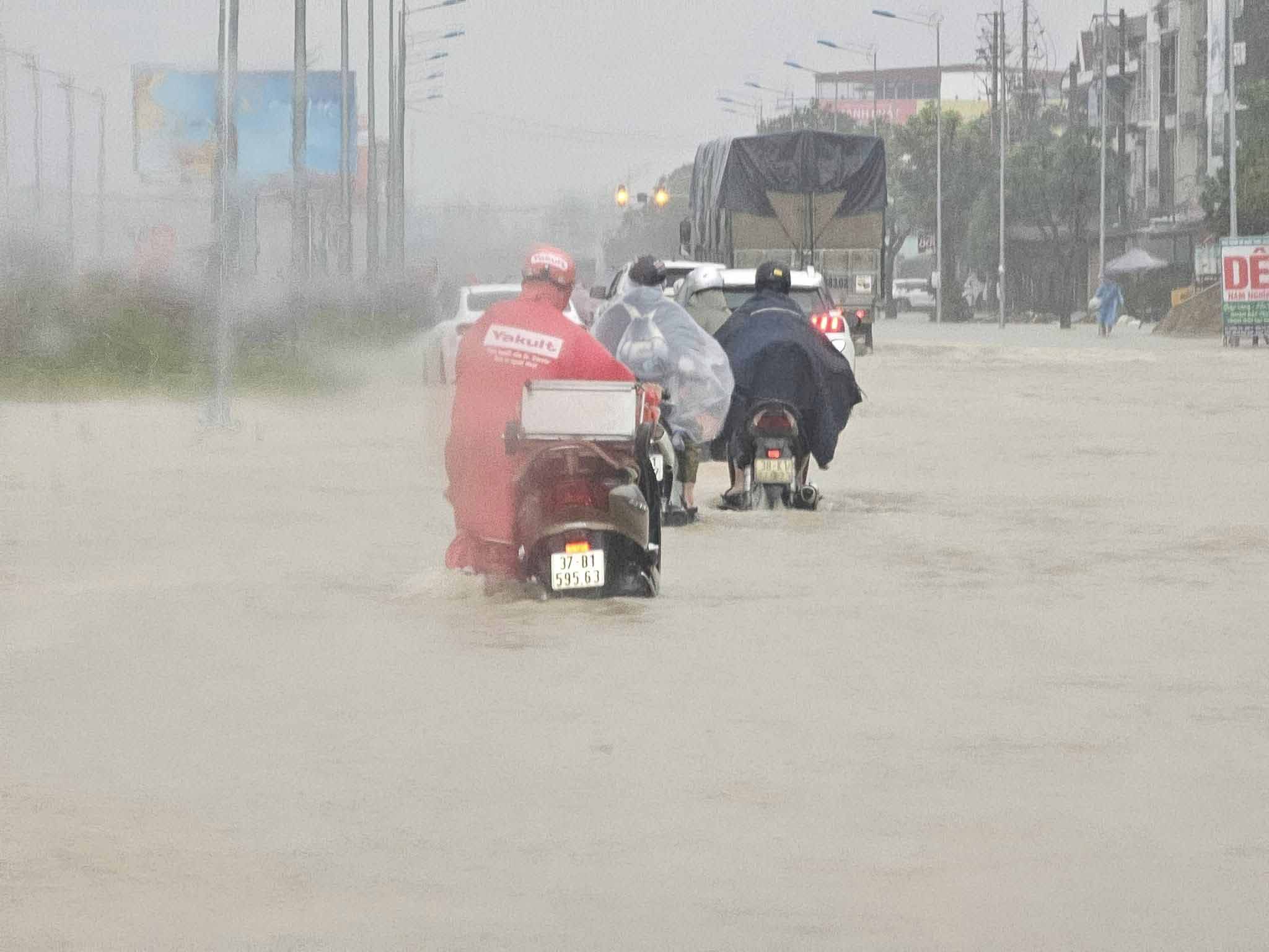 Người dân chật vật di chuyển do đường phố ở Vinh bị ngập. Ảnh: Quang Đại