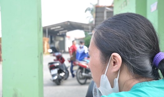 Chị Nguyễn Thị Huyền lo lắng đứng trước cổng Công ty TNHH T.T.B Việt Nam MFG chờ thông tin giải quyết vụ việc. Ảnh: Bảo Hân 