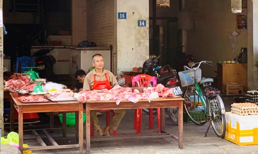 Anh Nguyễn Văn Mai - chủ quầy hàng kinh doanh thịt lợn tại chợ Quán Lau (phường Trường Thi, TP Vinh, Nghệ An) - ngồi chờ khách ghé mua thịt lợn. Ảnh: Quỳnh Trang