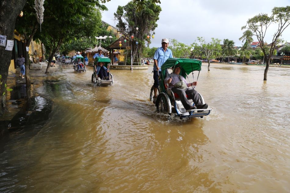 Ngoài lội lụt, một số du khách ngồi xích lô đi trong nước lũ.