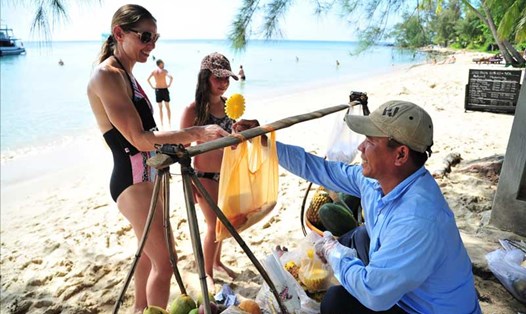 Du khách nước ngoài mua trái cây tươi từ một người dân địa phương tại một bãi biển ở Phú Quốc. Ảnh: Thế Duy