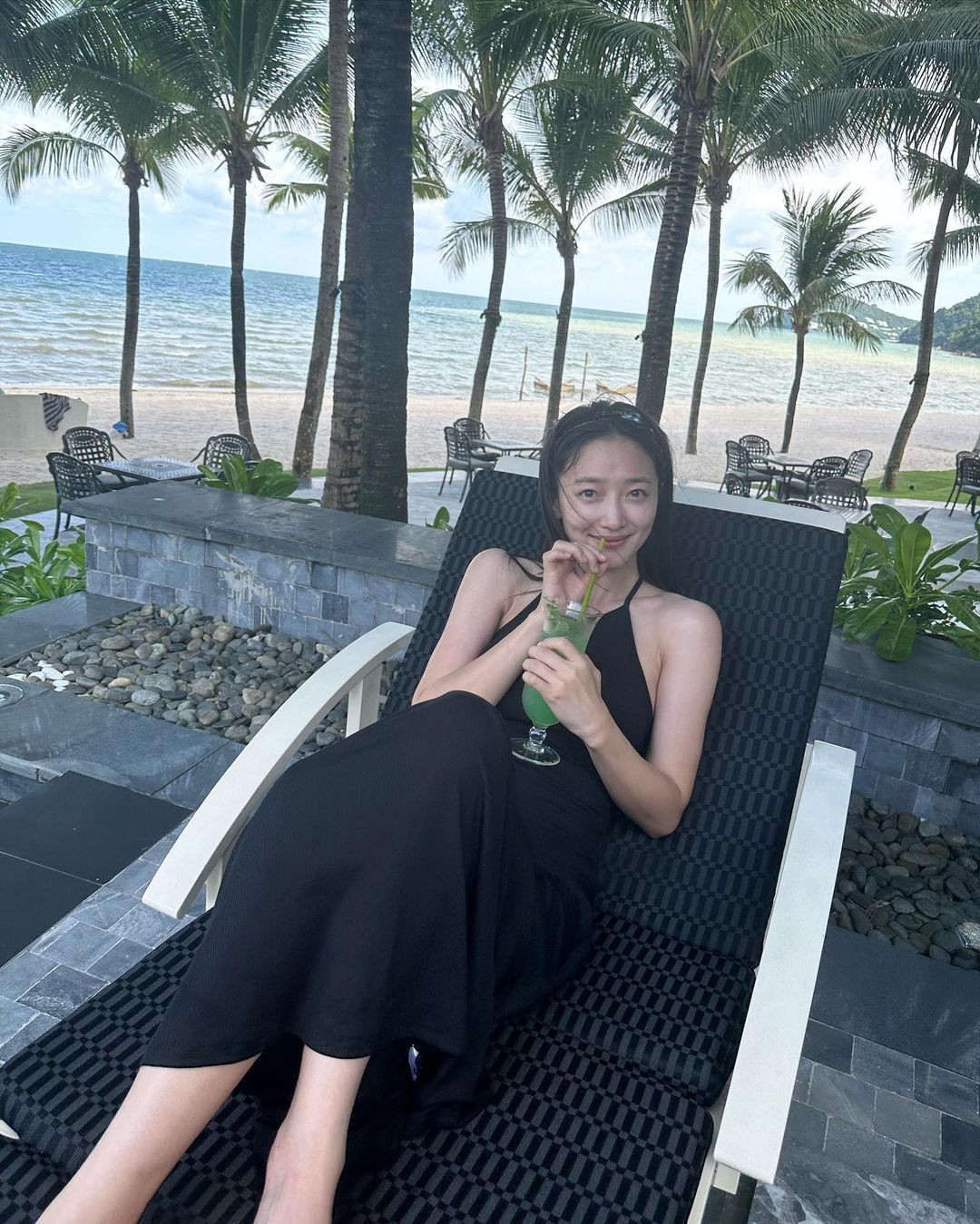 Pyo Ye Jin thưởng thức đồ uống trong khi ngồi ghế thư giãn gần bãi biển.