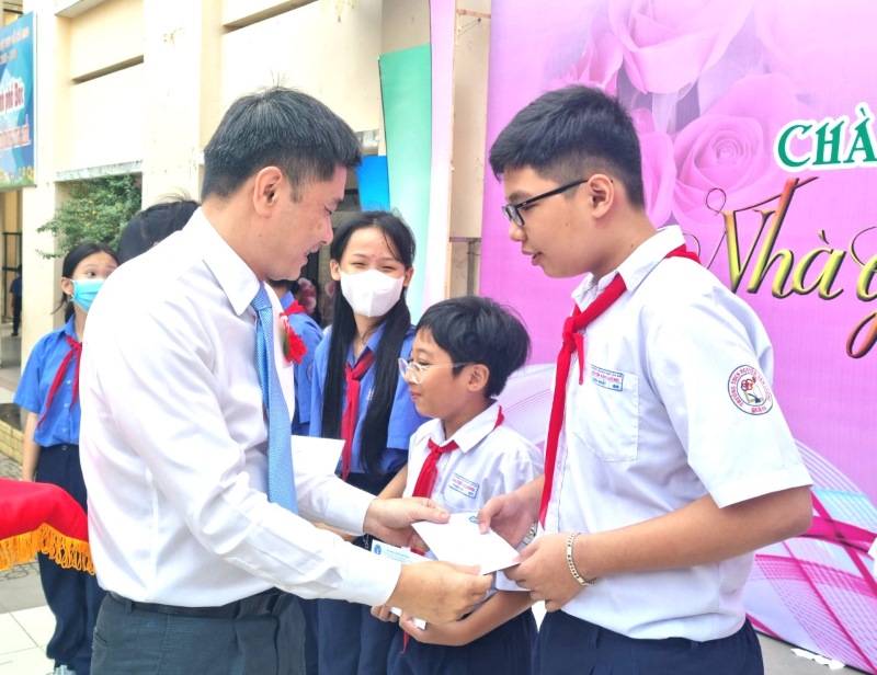 Ông Trần Dũng Hà (bìa trái) tặng học bổng cho các em học sinh co hoàn cảnh khó khăn của Trường THCS Nguyễn Văn Luông. Ảnh: Nam Dương