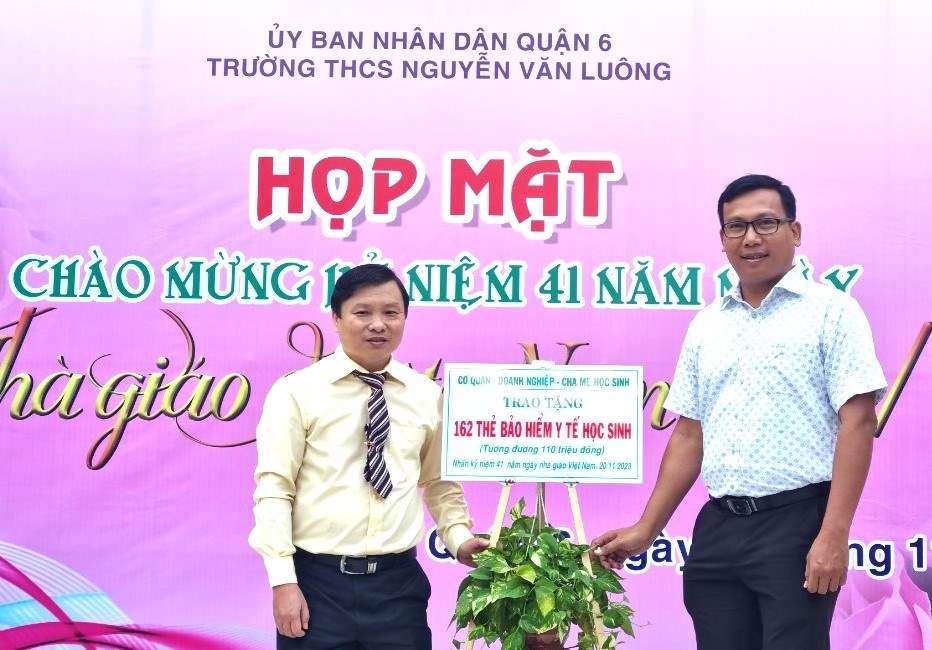 Đại diện các nhà hảo tâm (bên phải) tặng thẻ BHYT cho học sinh Trường THCS Nguyễn Văn Luông. Ảnh: Nam Dương