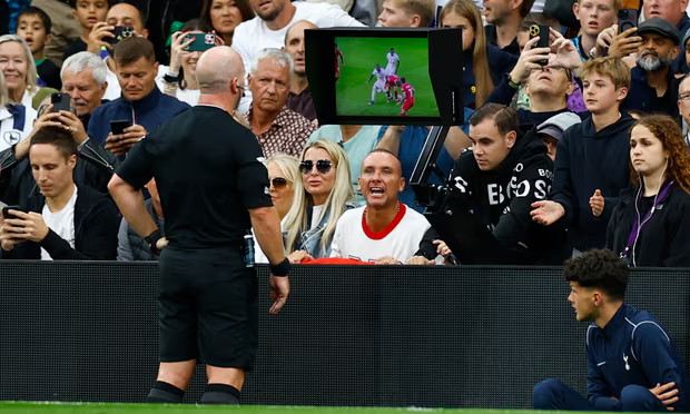 Trọng tài Simon Hooper nhìn vào màn hình VAR trước khi rút thẻ đỏ cho Curtis Jones của Liverpool trong trận gặp Tottenham.   Ảnh: AFP 