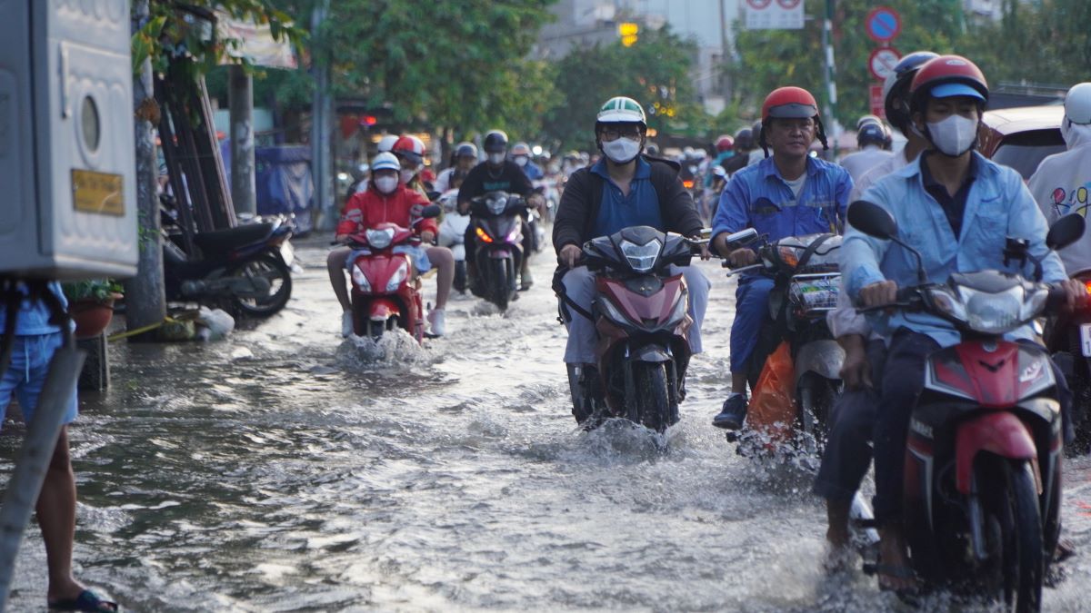 Ghi nhận của Lao Động, từ khoảng 16h30 nước từ kênh Tẻ bắt đầu dâng lên khiến mặt đường Trần Xuân Soạn bị ngập sâu từ 30-50 cm. 
