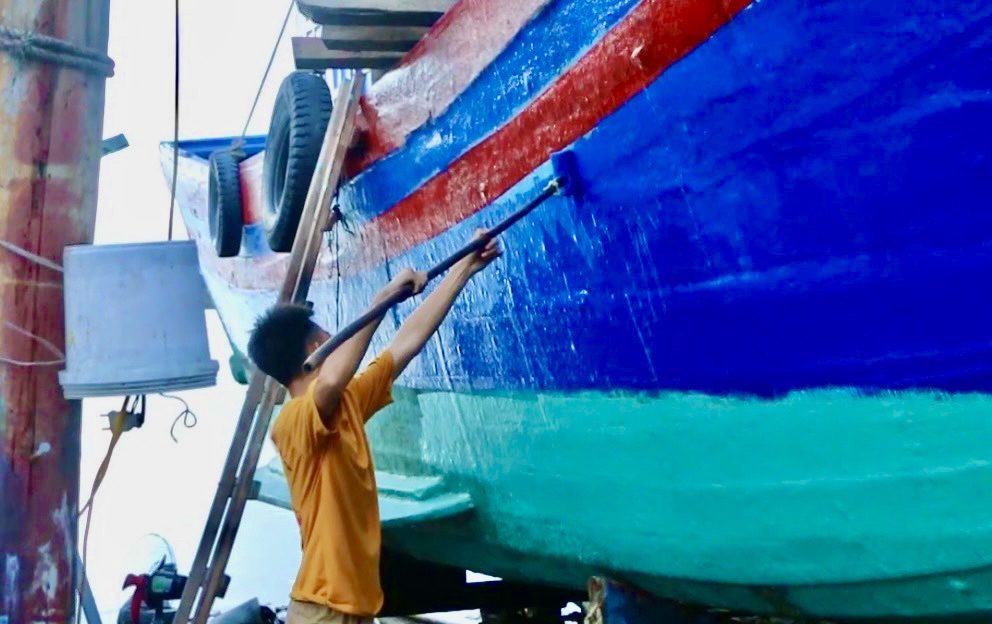 Để tăng độ chống nước vỏ tàu, công nhân phủ lưới nhựa sau đó phủ thêm lớp keo. Ảnh: Quỳnh Trang