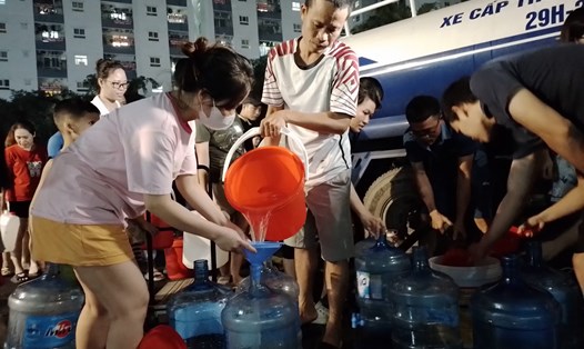 Người dân Khu đô thị Thanh Hà phải dùng xô, bình để lấy nước sạch về dùng. Ảnh: Anh Huy