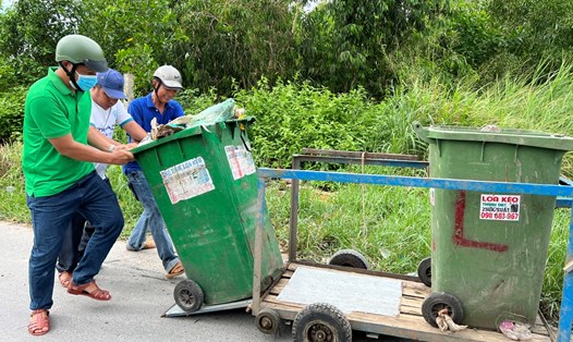 Các thành viên luân phiên vận chuyển thùng rác ra đường lớn để xe thu gom vận chuyển đến nơi xử lý rác. Ảnh: Nguyên Anh
