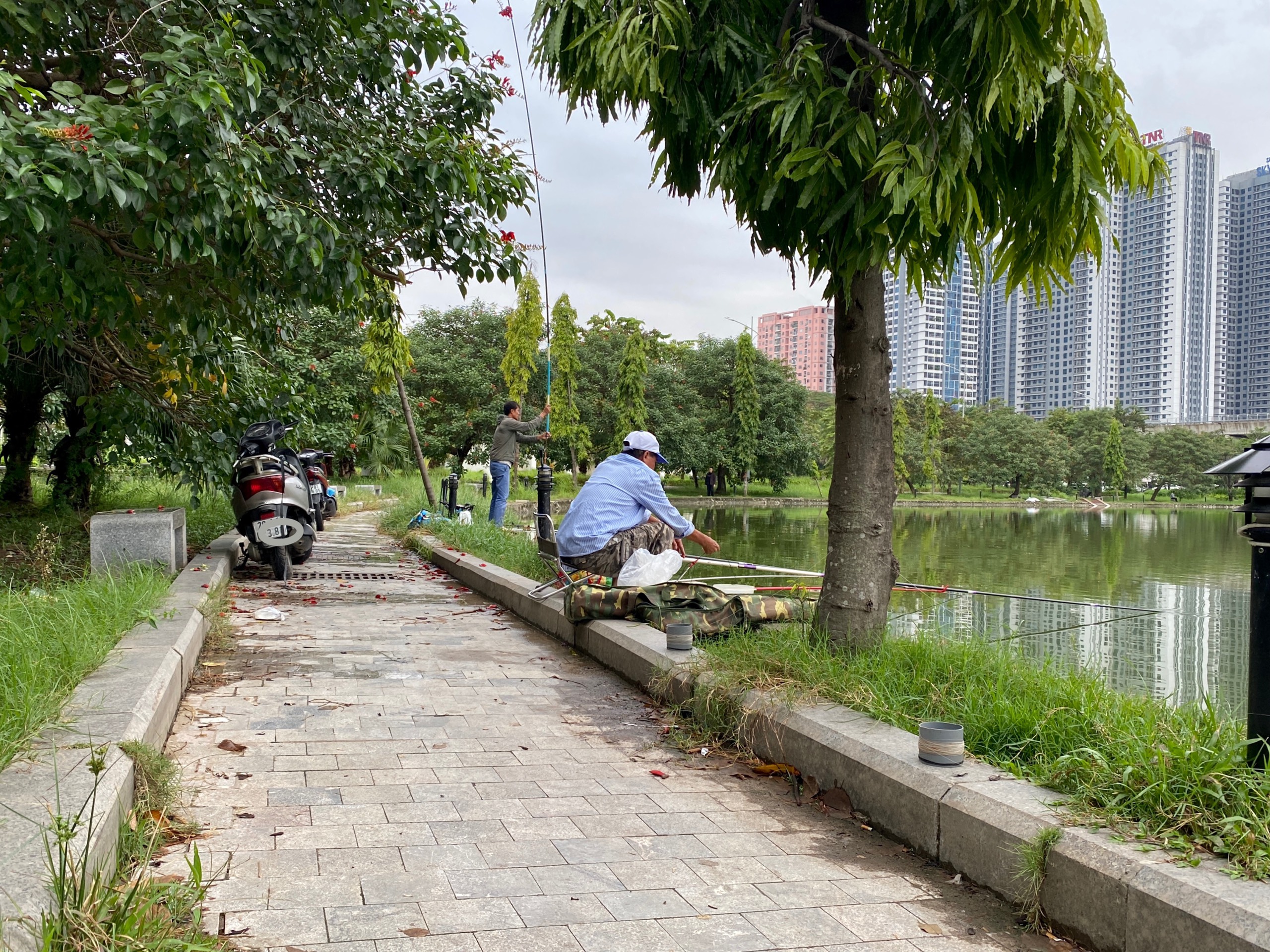 Người dân vô tư đi xe máy vào Công viên hồ điều hoà Mai Dịch câu cá. Ảnh: Vĩnh Hoàng