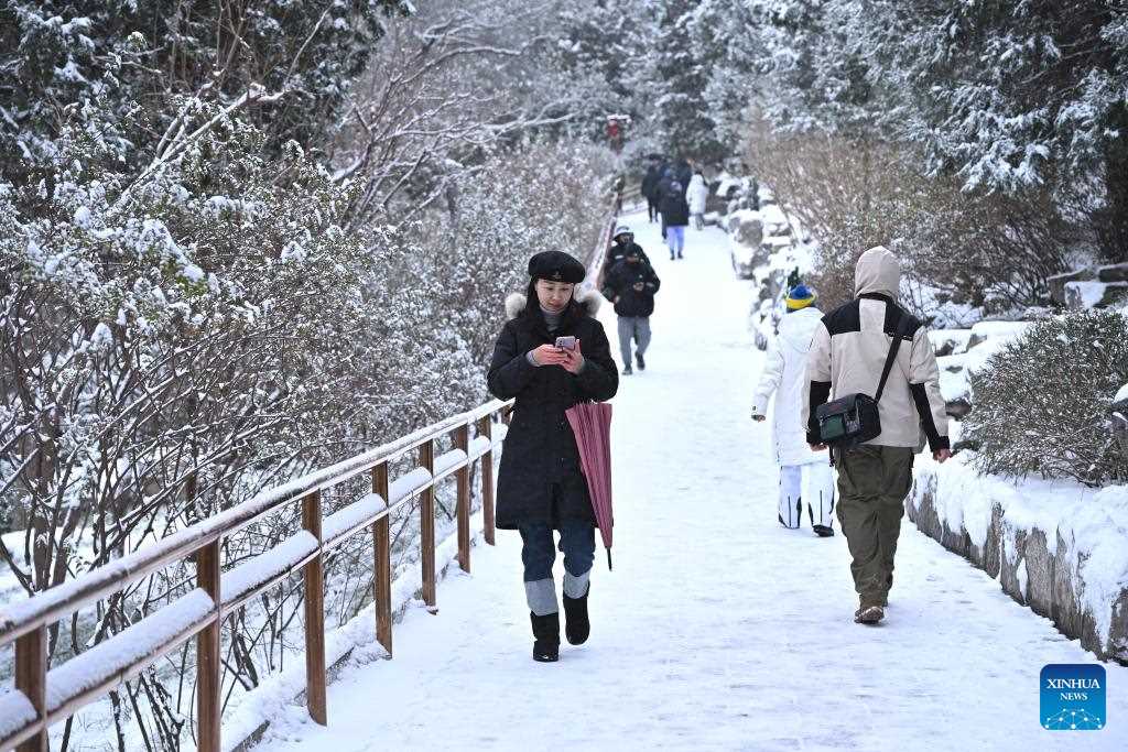 Người dân tham quan Công viên Cảnh Sơn giữa tuyết rơi ở Bắc Kinh, ngày 11.12.2023. Ảnh: Xinhua