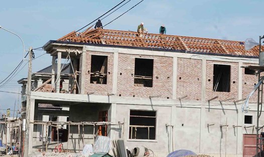 Tốp thợ đang khẩn trương hoàn thiện phần mái của ngôi nhà ở khu tái định cư cao tốc Bắc - Nam thuộc xã Kim Song Trường. Ảnh: Trần Tuấn.