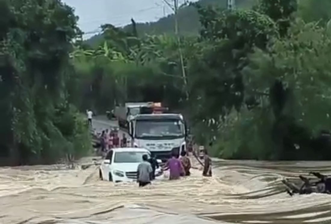 Mặc dù cầu tràn đang bị ngập nước lũ đổ về nhưng tài xế xe Mercedes vẫn cố chạy qua. Ảnh: Hải An
