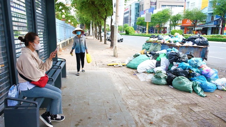 Người chờ xe buýt Cần Thơ đối diện với vòng vây rác thải. Ảnh: Phong Linh. 