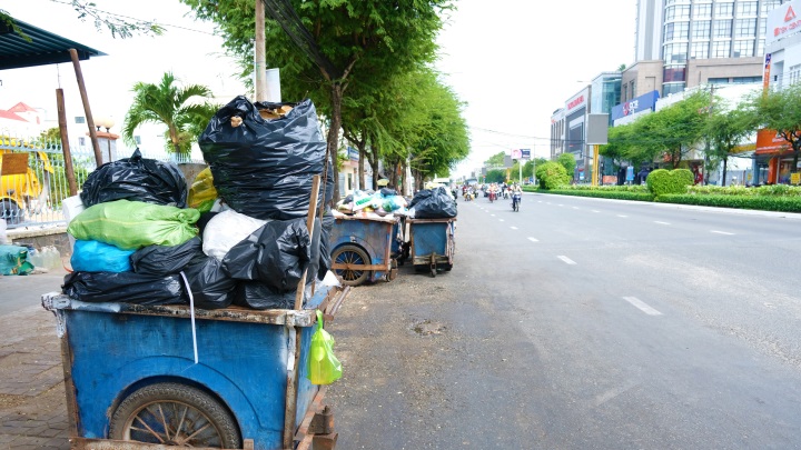 Nhiều xe rác đậu dưới lòng đường tạo thành điểm tập kết rác. Ảnh: Phong Linh