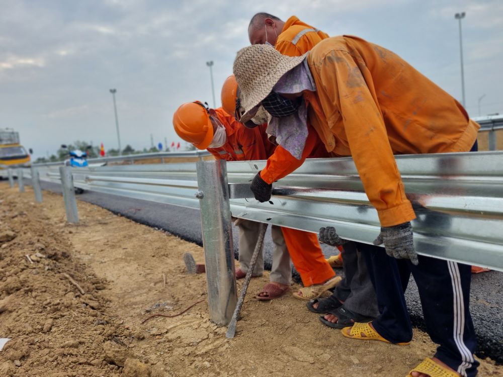 Công nhân đang lắp đoạn lan cuối cùng vào đường dẫn lên cao tốc Mỹ Thuận - Cần Thơ.
