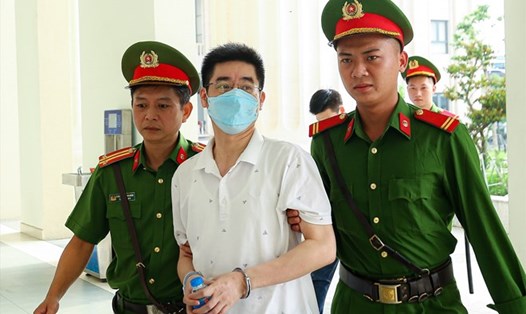 Cựu điều tra viên Hoàng Văn Hưng (giữa) khi bị dẫn giải tới phiên xử sơ thẩm vụ chuyến bay giải cứu. Ảnh: Quang Việt