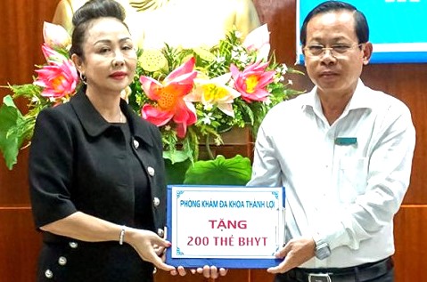 Giám đốc BHXH tỉnh Cà Mau tiếp nhận BHYT từ nhà tài trợ. Ảnh: Nhật Hồ