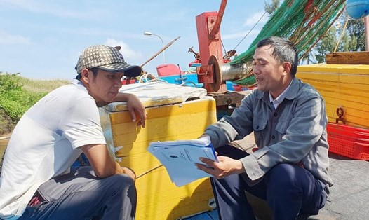 Cán bộ Trung tâm Đăng kiểm tàu cá tỉnh Quảng Ngãi hướng dẫn ngư dân xã Nghĩa An, TP Quảng Ngãi làm giấy tờ đăng kiểm cho tàu cá. Ảnh: Ý Thu
