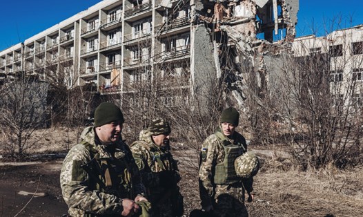 Binh sĩ Ukraina di chuyển trước một tòa nhà bị phá hủy ở Maryinka,  Donetsk. Ảnh chụp màn hình RT
