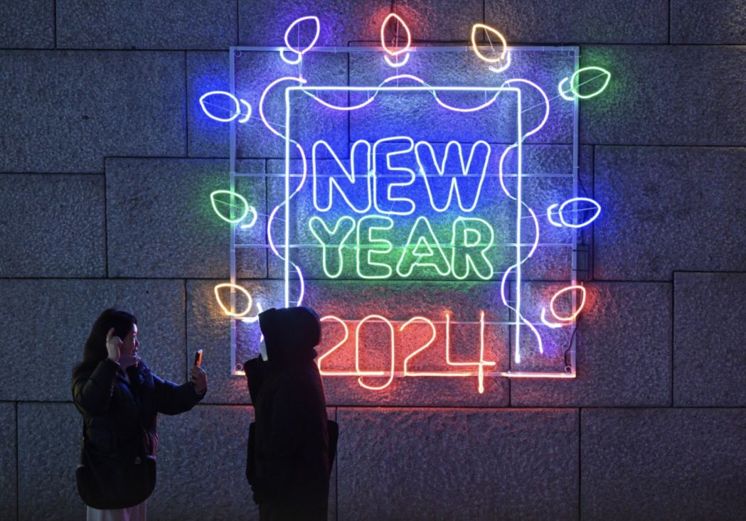 Người dân chụp ảnh trước màn đèn có dòng chữ “Năm mới 2024” ở trung tâm Seoul  (Hàn Quốc) ngày 22.12.2023. Ảnh: AFP