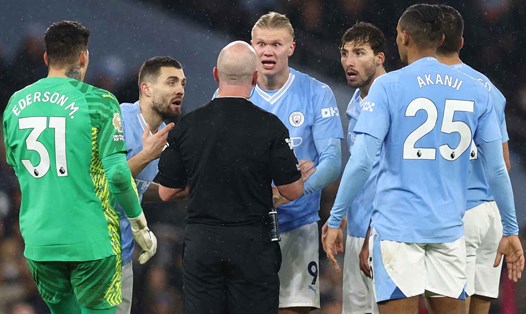 Các cầu thủ Man City vây lấy trọng tài Simon Hooper sau tình huống gây tranh cãi. Ảnh: AFP