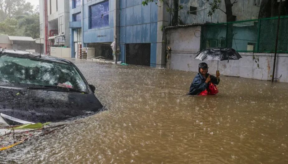 Một người đàn ông lội qua con đường ngập nước giữa cơn mưa lớn do bão Michaung ở Chennai, Ấn Độ, ngày 4.12.2023. Ảnh chụp màn hình