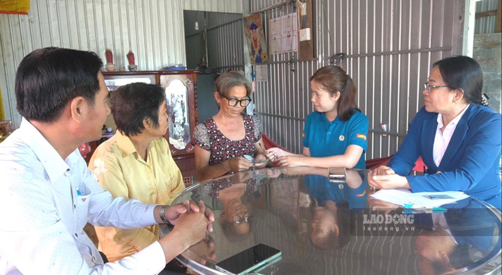 Phóng viên báo Lao Động trao tiền hỗ trợ của bạn đọc cho gia đình chị Võ Thị Tươi. Ảnh: Xuân Nhi