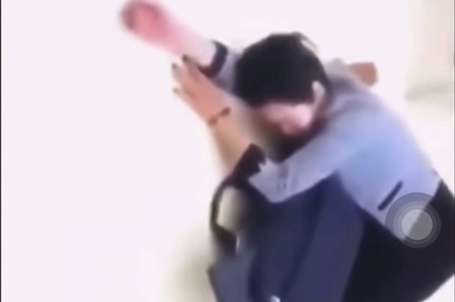 Cô giáo H nằm ra đất sau khi bị một số học sinh ném vật thể lạ vào người. Ảnh cắt từ clip