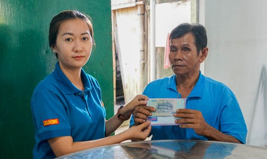 Phóng viên Báo Lao Động trao tiền hỗ trợ của bạn đọc cho gia đình ông Sơn Ngọc Hải. Ảnh: Trường Khoa