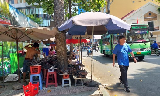 Chiếm dụng vỉa hè đường Nguyễn Thái Bình (quận 1) làm nơi buôn bán, người dân phải đi bộ dưới lòng đường. Ảnh: Minh Quân