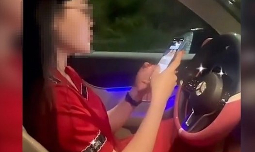 Nữ tài xế vừa buông hai tay khỏi vô lăng, vừa dùng điện thoại để bạn quay TikTok. Ảnh cắt từ clip