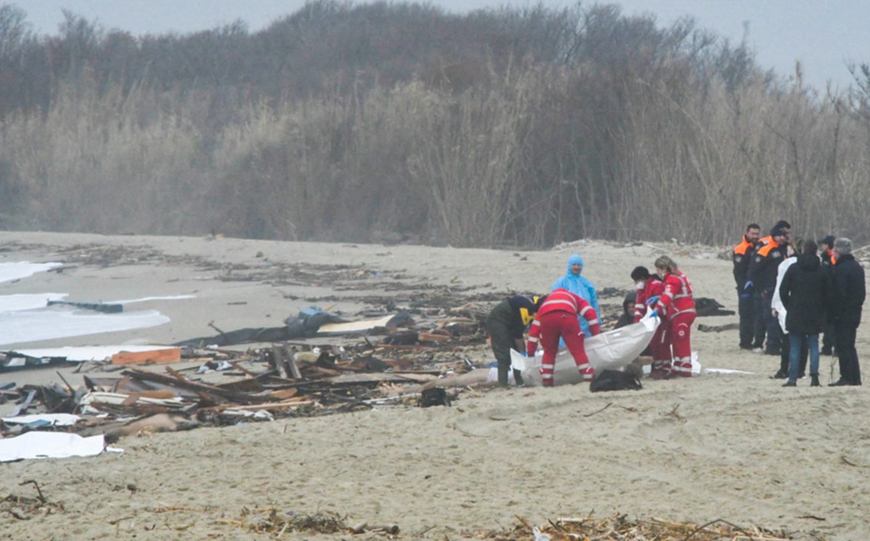 Lực lượng cứu hộ xử lý túi đựng thi thể tại địa điểm xảy ra vụ đắm thuyền chở người di cư ở Italia ngày 26.2.2023. Ảnh: ANSA