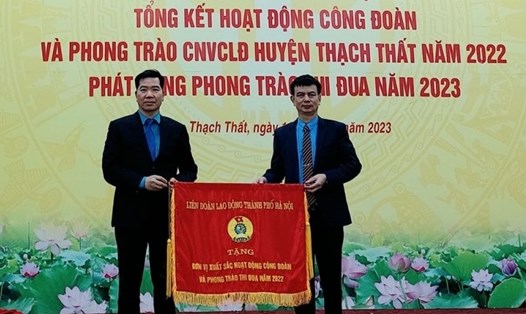 Ông Nguyễn Huy Khánh - Phó Chủ tịch Liên đoàn Lao động thành phố Hà Nội (bên trái) trao Cờ thi đua xuất sắc năm 2022 cho Liên đoàn Lao động huyện Thạch Thất. Ảnh: Hải Yến