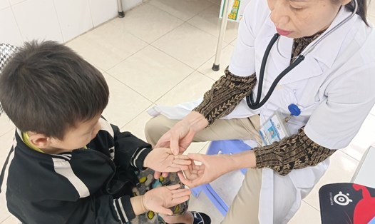 Bác sĩ trạm Y tế xã Đồn Đạc thăm khám cho trẻ bị bệnh tay chân miệng. Ảnh: Đoàn Hưng