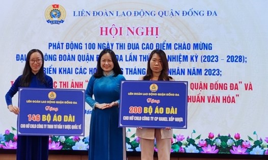Bà Lê Thị Kim Huệ - Chủ tịch Liên đoàn Lao động quận Đống Đa (đứng giữa) trao biển tượng trưng tặng áo dài cho nữ công nhân lao động 2 Công ty. Ảnh: Hải Yến