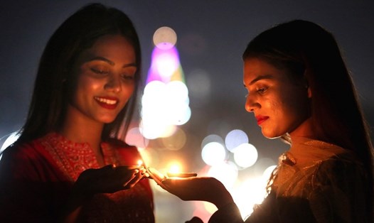 Những người phụ nữ thắp đèn vào đêm trước lễ hội ánh sáng Diwali ở Bhopal, Ấn Độ năm 2022. Ảnh: Xinhua