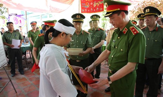 Chị Trần Thị Phương (vợ Trung tá Hào) nhận quyết định truy thăng cấp bậc từ Thứ trưởng Nguyễn Duy Ngọc. Ảnh: An Long