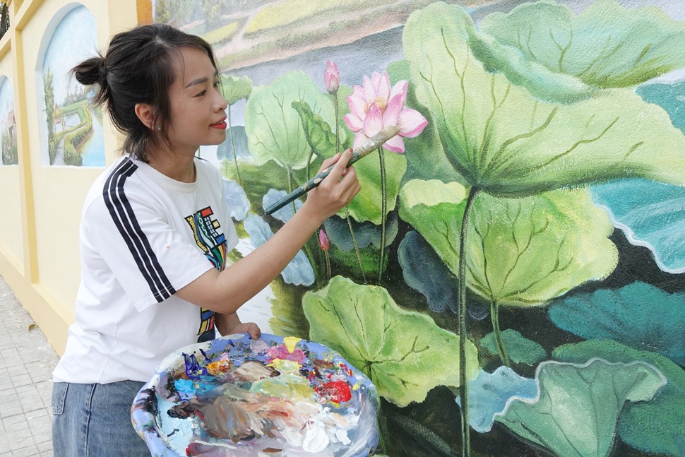 Chị Nguyễn Thị Thu Hà - Giáo viên Mỹ thuật Trường Tiểu học Thạch Trung (TP Hà Tĩnh) - trưởng nhóm vẽ tranh tô điểm phố ẩm thực Nguyễn Du hoàn thiện một bức bích hoạ. Ảnh: Trần Tuấn