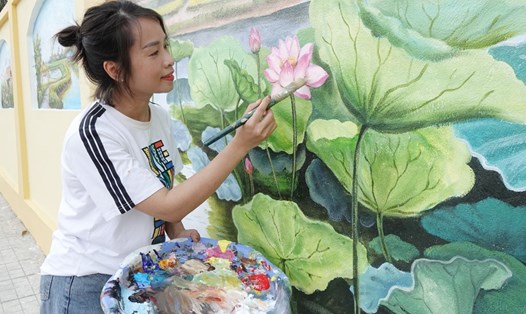 Chị Nguyễn Thị Thu Hà - Giáo viên Mỹ thuật Trường Tiểu học Thạch Trung (TP Hà Tĩnh) - trưởng nhóm vẽ tranh tô điểm phố ẩm thực Nguyễn Du hoàn thiện một bức bích hoạ. Ảnh: Trần Tuấn