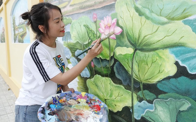 Chị Nguyễn Thị Thu Hà - Giáo viên Mỹ thuật Trường Tiểu học Thạch Trung (TP Hà Tĩnh) - trưởng nhóm vẽ tranh tô điểm phố ẩm thực Nguyễn Du hoàn thiện một bức bích hoạ. Ảnh: Trần Tuấn